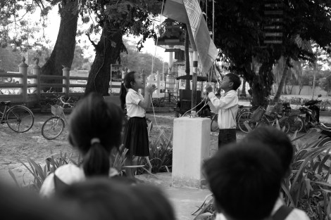 To finalize school hours, Chan Chao Loy (or ‘Loy’, right), a 12 year old waste picker and his class mate are taking down a national flag in school’s playground. (Photo © Lee Yu Kyung 2013) 