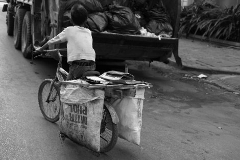Chan Chao Loy (or ‘Loy’), a 12 year old, is pushing hard his brake-broken bicycle seemingly to attempt to pass ahead garbage truck. He is one of thousands waste picking children in Cambodia. His both parents are HIV positive.(Photo © Lee Yu Kyung 2013) 