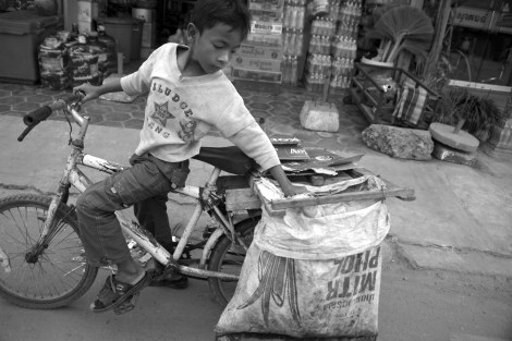 Chan Chor Loy (or ‘Loy’), a 12 year old waster picker in Cambodia, is reorganizing his collected recycling materials before moving ahead. (Photo © Lee Yu Kyung 2013) 