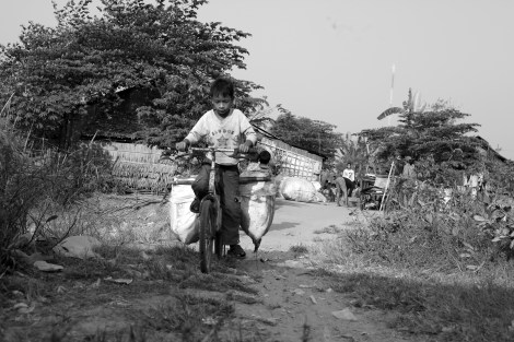 Chan Chor Loy (or 'Loy') is arriving his neighborhood from working field, in which he has picked plastics, cans, papers and other recycling materials. Loy is one of thousands waste picking children in Cambodia. (Photo © Lee Yu Kyung 2013) 