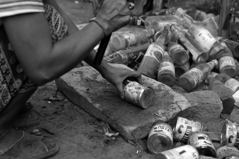 Loy’s mother, who is also waster picker is crashing cans flat before selling. 1 kilogram of cans can be sold for 200 riels (approximately 5 cent) (Photo © Lee Yu Kyung 2013) 