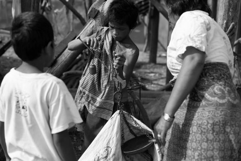 Waste pickers in Phnom Khnom, one of many villages near Tonle Sap Lake in Siem Reap in Cambodia, are scaling their collected recycling materials. Woman (right) buys recycling materials from children who all are waste pickers. (Photo © Lee Yu Kyung 2013) 