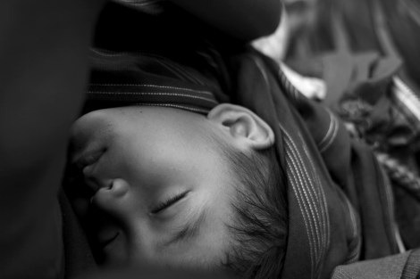 An IDP child on a rickety truck sleeping while traveling on cliffside dirt road (Photo © Lee Yu Kyung 2013)