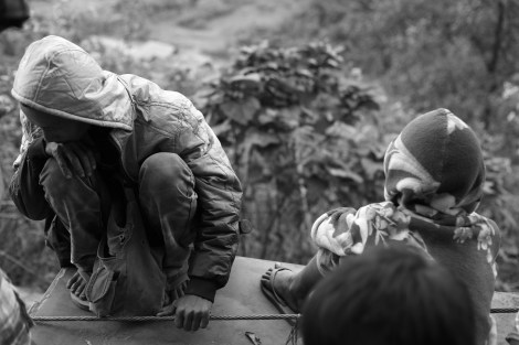 An IDP man and a child sitting  on the truck which is transporting them to safe place through the cliffy bumping road in Mansi Township. (Photo © Lee Yu Kyung 2013)